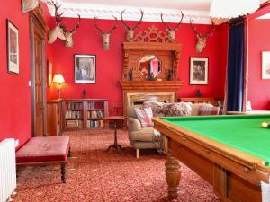 a living room with red walls and a pool table at Braeriach - Mar Lodge Estate in Ballater
