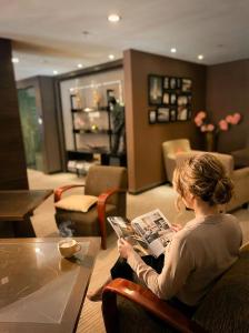a woman sitting at a table reading a magazine at Imperial Heritage Hotel Melaka I City Centre I Free Wifi I Free Parking l Free Club Lounge Access in Malacca