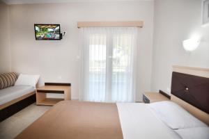 a bedroom with a bed and a couch and a window at EXOHI STUDIOS in Sarti