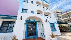 a white building with a blue door at 海灘戀情 Beach Love 近沙灘-國旅卡特約商店 陽台房 希臘地中海風格 in Eluan