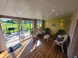 a living room with a deck with chairs and tables at Les Gîtes de la chapelle blanche in Anor