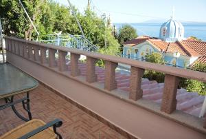 a balcony with a fence and a house on the water at Paris-Irini Studios And Apartments in Plomarion