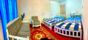 a bedroom with two beds and a chair and a carpet at Peradeniya Inn in Kandy