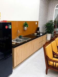 a kitchen with a sink and a counter with yellow chairs at Punica Homestay in Tuy Hoa