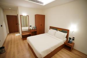 a bedroom with a large white bed and a mirror at Hotel Grand Vekasa in Salem