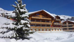 un rifugio da sci nella neve con un albero di Hotel L'Etable a Les Crosets