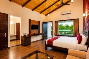 ein Schlafzimmer mit Bett, Fernseher und Sofa in der Unterkunft Baris river resort Corbett in Rāmnagar
