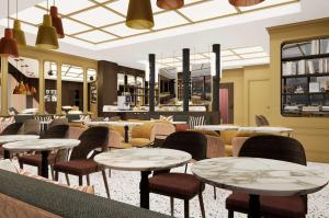 a restaurant with tables and chairs in a room at Grand Hôtel De Turin in Paris