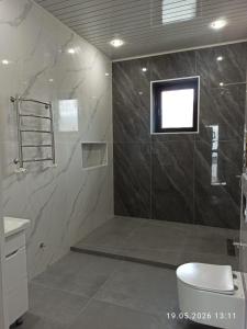 a bathroom with a shower with a toilet and a window at Village House in Zhabagly