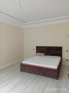 a bed in an empty room with a white wall at Village House in Zhabagly