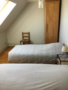 a bedroom with two beds and a wooden chair at Maison 1er étage chéreng 6kms stade Pierre Mauroy 4 personnes in Chéreng