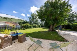 a patio with a table and chairs and a tree at Studio Bord-Eau, terrasse et jardin in Saint-André-de-Cubzac