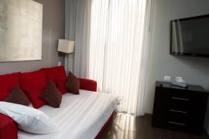 a bedroom with a red couch and a flat screen tv at Suites Ganges in Mexico City