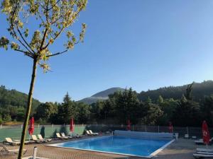 a swimming pool with chairs and a mountain in the background at Camping 3 étoiles - Piscine - ccbgccf in Rennes-les-Bains +20 photos