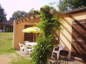 a patio with a table and chairs and an umbrella at Camping 3 étoiles - Piscine - ccbgbeh in Puy-lʼÉvêque