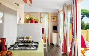 a kitchen with a stove and a white refrigerator at Camping 3 étoiles - Piscine - ccbgaig in Loubeyrat