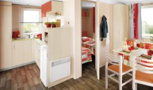 a small kitchen with a table and a bed in a room at Camping 3 étoiles - Piscine - ccbgaig in Loubeyrat