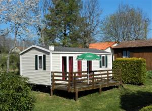 a small white house with an umbrella and a bench at Camping 3 étoiles - Piscine - ccbgaig in Loubeyrat