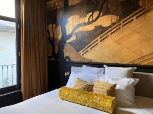 a bed with white pillows and a painting on the wall at Gilded Ox Suites in Deventer