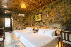 two beds in a room with a stone wall at Laco Green Trang An in Yên Ha