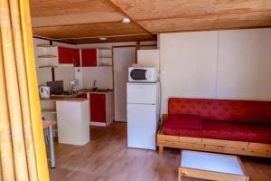 a living room with a red couch and a kitchen at Chalet 2 étoiles - Piscine - ccbgdfh in Porto-Vecchio