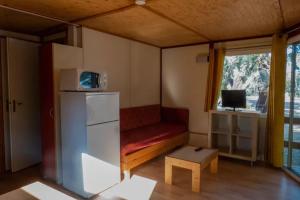 a small room with a red couch and a refrigerator at Chalet 2 étoiles - Piscine - ccbgdfh in Porto-Vecchio