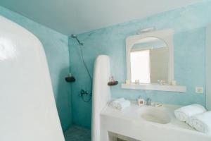 a blue bathroom with a sink and a mirror at Almond Deluxe Suite in Santorini