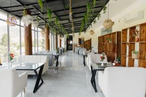 a restaurant with white chairs and tables and windows at The Twelve Petals by Parvati Inn in Dhikuli