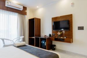 a hotel room with a bed and a flat screen tv at The Twelve Petals by Parvati Inn in Dhikuli