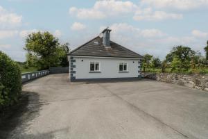 a white house with a black roof on a driveway at River House in Ballina