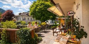 two people sitting at tables on a patio at Ferienhof Alte Post in Weissbriach
