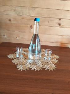 a bottle and two glasses on a wooden table at RIVERSTONE Drašković camp and bungalows in Nikšić