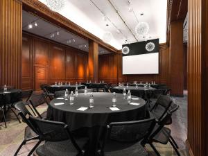 a conference room with tables and chairs and a screen at 21c Museum Hotel Durham in Durham