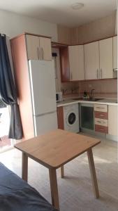 a kitchen with a table and a white refrigerator at SERVILUX 4 in Torremolinos +3 photos