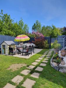a patio with benches and an umbrella in a yard at Gite Agnès & J-Pierre en étage Evasion spa option in Pierre-Châtel
