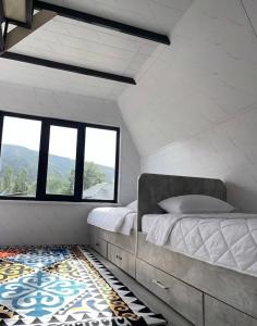 a bedroom with a bed and a window and a rug at A frame house with a view of mountains in Karakol