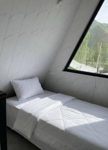 a white bed in a room with a window at A frame house with a view of mountains in Karakol
