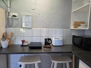a kitchen with a counter with a microwave and two stools at Azalea at Greenway Woods in White River