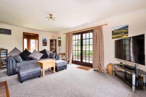a living room with a couch and a tv at Finest Retreats - The Grove Annexe in Craven Arms