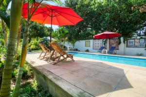 two chairs and red umbrellas next to a pool at Ilha Azul in Ponta do Ouro +20 photos