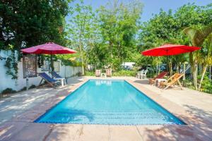 a swimming pool with two umbrellas and chairs at Ilha Azul in Ponta do Ouro