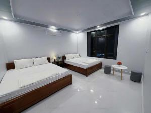 a white room with two beds and a window at Jade River Phong Nha in Phong Nha