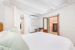a white bedroom with a bed and a window at Casa del Call in Palma de Mallorca