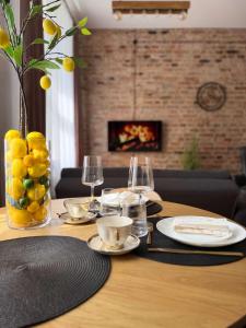 a table with plates and glasses and a vase of lemons at Urban Loft Studio 33 in Daugavpils +11 photos