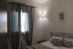 a bedroom with a bed and a window with curtains at Baia dei Fenici in Birgi Vecchi