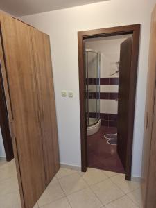 a hallway with two wooden doors and a bathroom at Apartman Krivičić in Cres