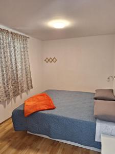 a bedroom with a bed with an orange blanket at Apartman Krivičić in Cres