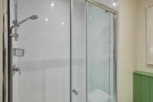 a shower with a glass door in a bathroom at The Bamburgh Bolthole in Bamburgh +22 photos