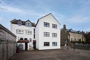 a white house with black windows on a street at The Bamburgh Bolthole in Bamburgh