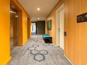 a corridor of a hospital hallway with a green bench at Mercure Canberra Belconnen in Canberra